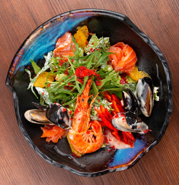 istock Seafood salad: shrimp, mussels and salmon, arugula and oranges. In a decorative plate 1282445566