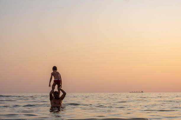 Father and son feeling grateful for spending time together in the beach during the sunset