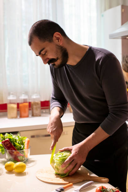 istock Man Cutting Fresh Lettuce at the Kitchen 1282447259