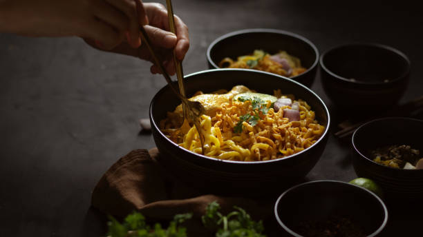 istock Hand holding silverware to eating Noodles curry soup with Chicken (Khao Soi) 1282448061