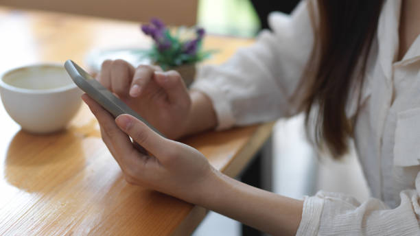 istock Female hands using smartphone on wooden table in coffee shop 1282448133