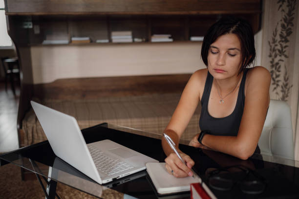 istock Young female student using laptop, communicates on internet with teachers. 1282449046