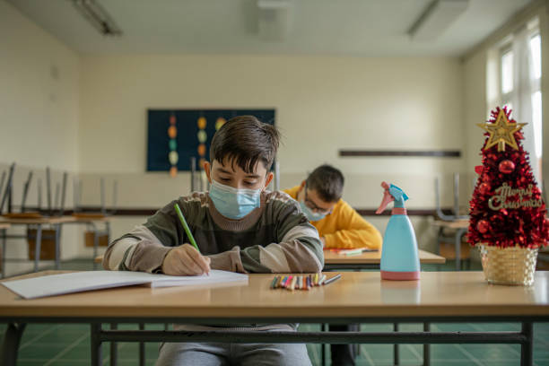 istock Two school boys writting and studying in the classroom with protective face masks on 1282449405