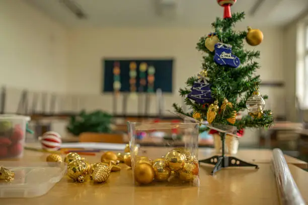 Chritmas tree and decorations on a desk in an empty classroom in time of coronavirus.