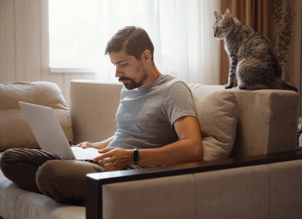Young attractive smiling guy is browsing at his laptop