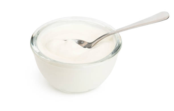 White yogurt in a glass bowl and spoon isolated with soft shadow stock photo