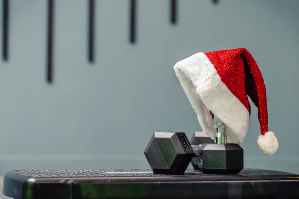 cierra el sombrero de papá noel en el gimnasio. - holiday healthy lifestyle weight christmas fotografías e imágenes de stock