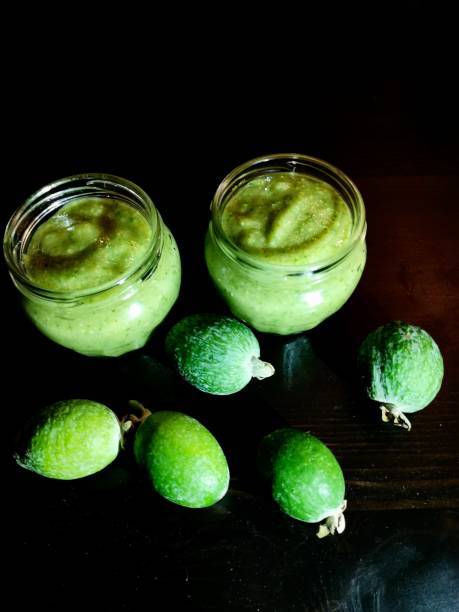 istock Two glass jars with mashed feijoa with sugar and fresh feijoa on a black table background 1282452918