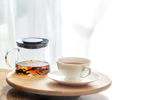 A glass teapot with tea and a cup of tea on the table