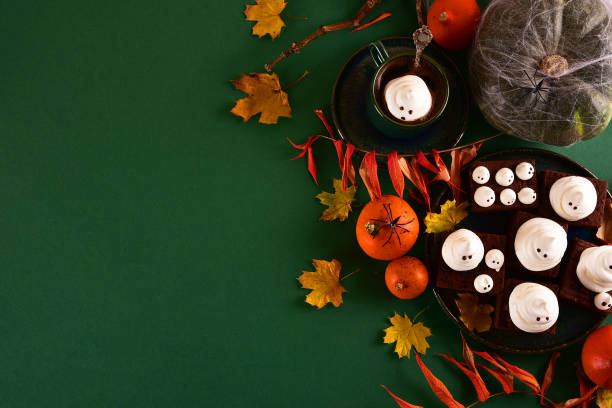 istock Halloween-themed concept: sugar ghosts, pumpkins, coffee on a dark green background. 1282454170