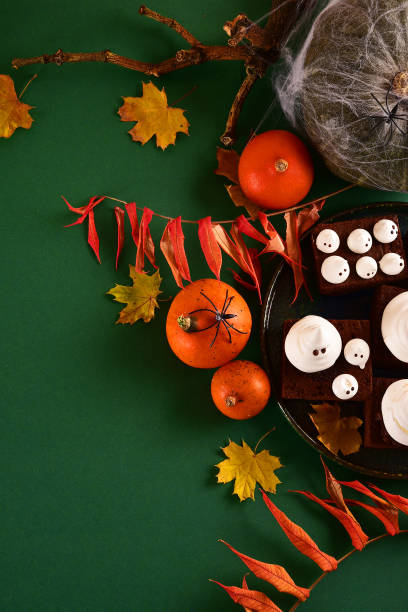 istock Halloween-themed concept: sugar ghosts, pumpkins, coffee on a dark green background. 1282454242