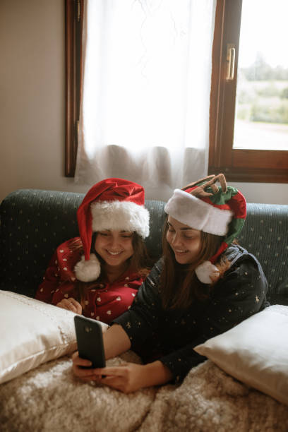 istock Twin sisters on Christmas using phone 1282455464