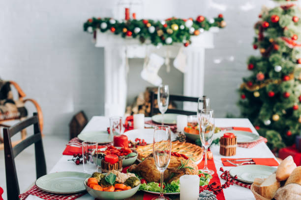 istock selective focus of table served with festive dinner, christmas tree and fireplace with decorated spruce branch on background 1282456059
