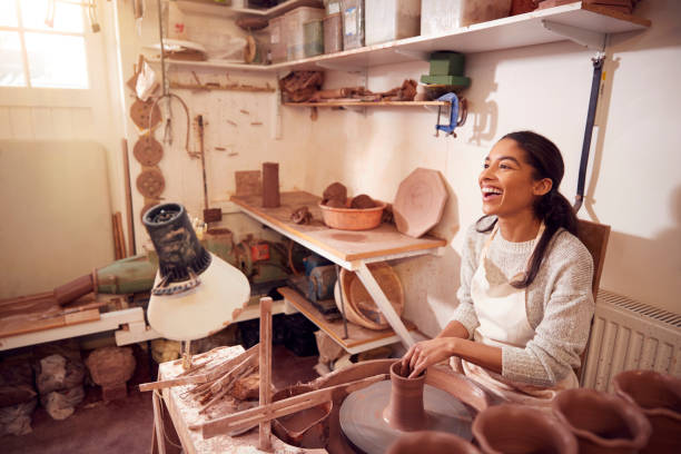 potter femelle shaping argile pour pot sur la roue de poterie dans le studio de céramique - throwing wheel photos et images de collection