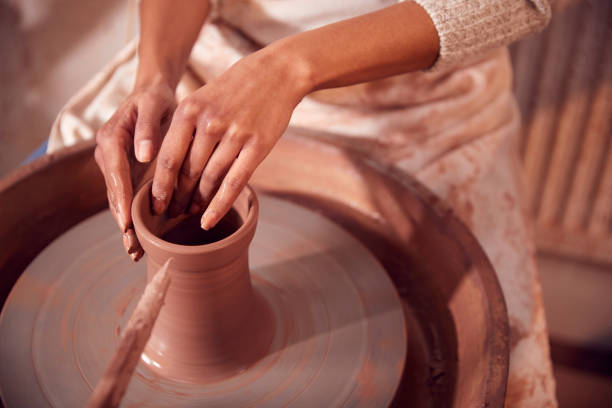 close up of female potter shaping clay for pot on pottery wheel in ceramics studio - throwing wheel fotografías e imágenes de stock