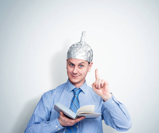 funny man in an aluminum foil hat holds a book and preaches. concept art phobias - tin foil hat imagens e fotografias de stock