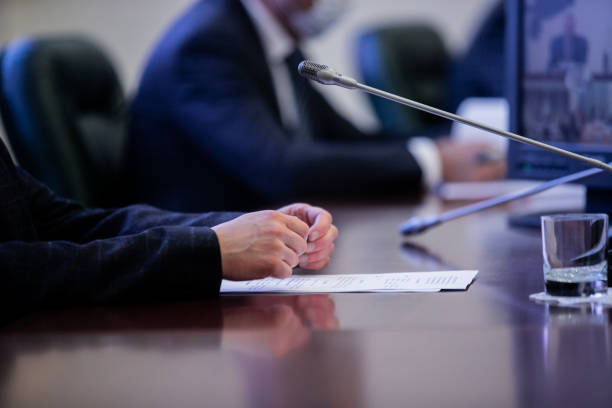 One of politician sitting by table with his hands over document during political summit or conference stock photo
