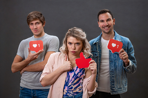 Group of young adult people holding a social media icons in their hands in studio with dark grey background.