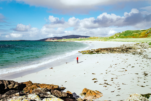 Woman strolling on Prince's Beach on the island of Eriskay, part of the Outer Hebrides of Scotland. In Gaelic, Coilleag a'Phrionnsa, it is where Bonnie Prince Charlie landed from France to lead the Jacobite Rebellion of 1745.