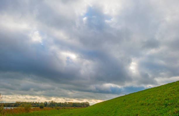 istock Dike under rain clouds in a blue dark sky in bright sunlight in autumn 1282461195