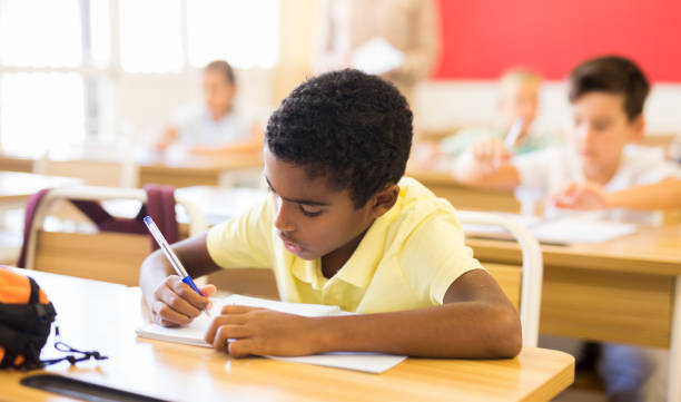 istock Schoolboy sitting at desk studying in classroom 1282462013