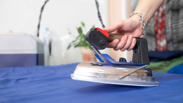 istock large, heavy, metallic iron in textile workshop. woman ironing cloth for tailoring. production of clothes 1282462075