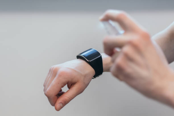 istock casual man spraying alcohol antiseptic on his smart watch 1282463396