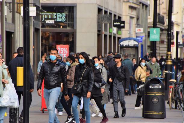 People wearing face masks on Oxford Street, London London, United Kingdom - October 7 2020: People wearing face masks on a crowded Oxford Street, daytime view covent garden photos stock pictures, royalty-free photos & images