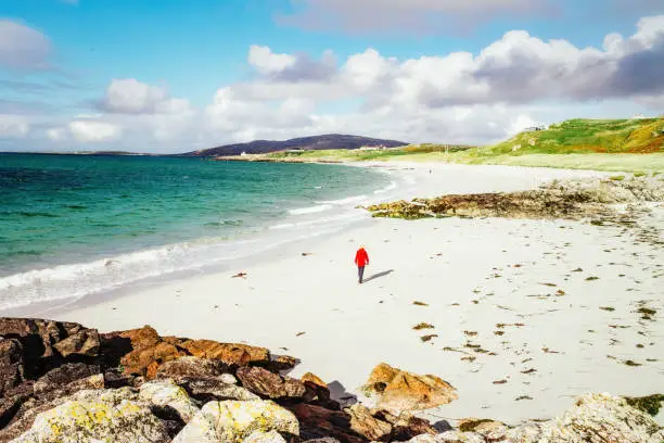 Woman strolling on Prince's Beach on the island of Eriskay, part of the Outer Hebrides of Scotland. In Gaelic, Coilleag a'Phrionnsa, it is where Bonnie Prince Charlie landed from France to lead the Jacobite Rebellion of 1745.