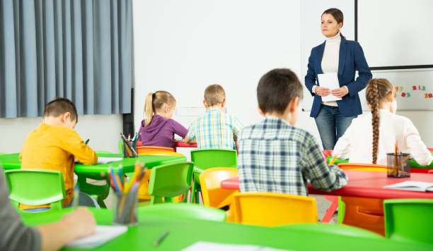 istock Female teacher and pupils working in classroom at elementary school 1282465256