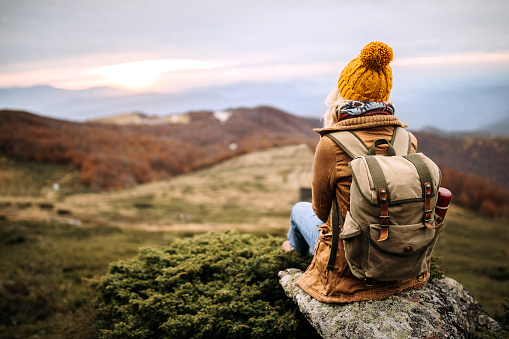 Rare view of female hiker resting on a mountain rock