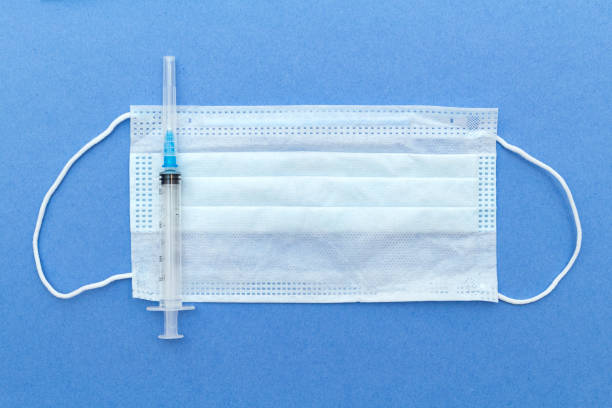 istock medical protective mask, syringe with copy space on a blue background. 1282468165
