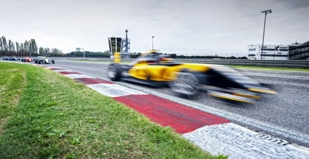Blurred motion of open-wheel single-seater racing car cars driving on track.