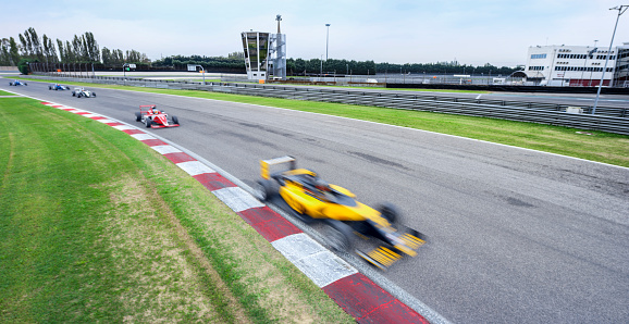 Blurred motion of open-wheel single-seater racing car cars driving on track.