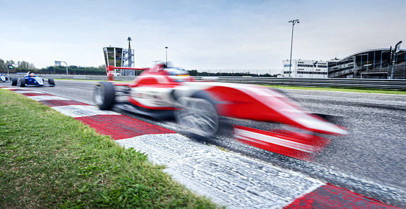 Blurred motion of open-wheel single-seater racing car cars driving on track.