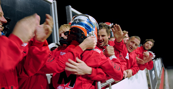Pit crew and racing driver celebrating his victory.