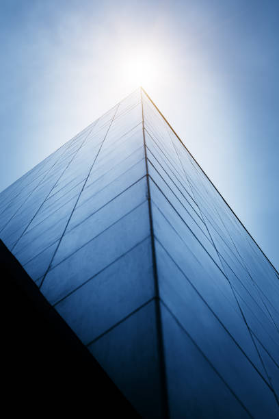 looking up at the city"u2019s tall buildings from a low angle, the side of the building has a triangular pyramid - window sun sunlight vertical imagens e fotografias de stock