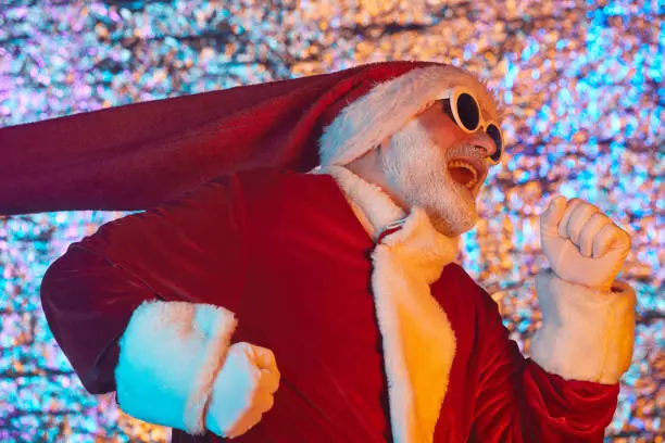 Bearded man in sunglasses and in Santa costume running to the party