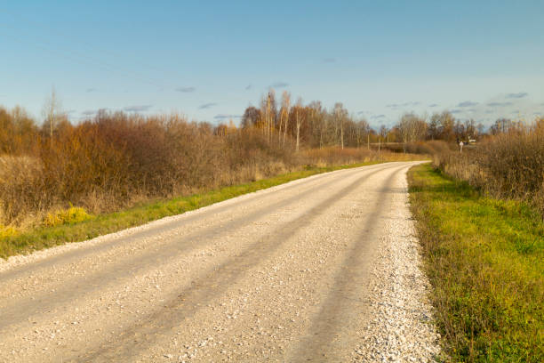 The Autumn landscape with expensive in rural terrain on background blue sky. Road coverring gravel