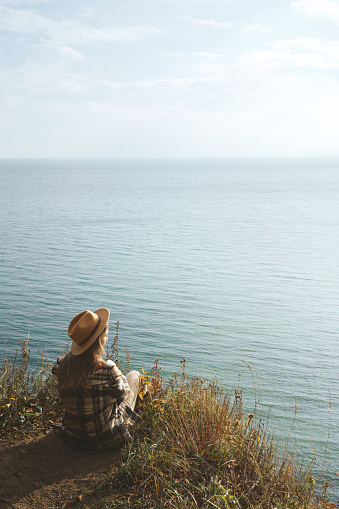 Woman sitting alone on the edge of the cliff and enjoying the view