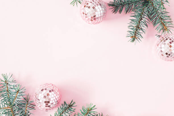 Christmas composition. Frame made of fir tree branches, pink balls on pastel pink background. Christmas, winter, new year concept. Flat lay, top view, copy space