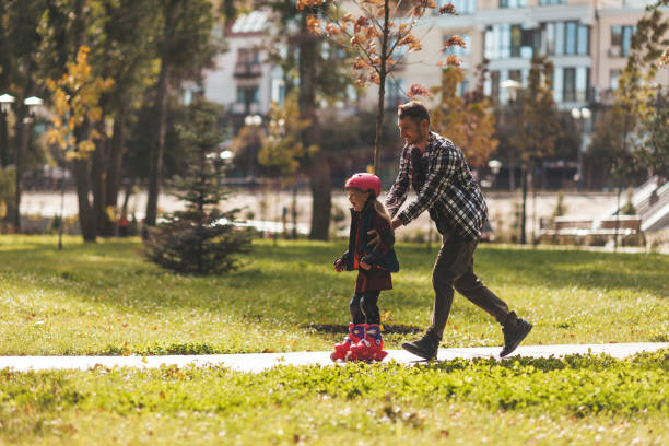 istock Dad and daughter roller-skate in the park. Leisure weekend together 1282478201