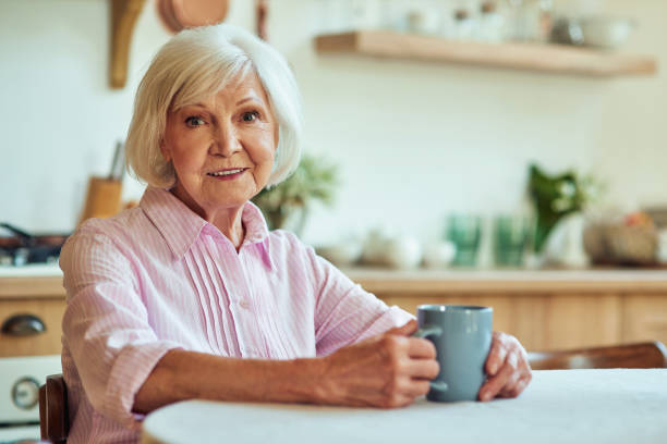 istock Smiling elder woman drinking tea at home 1282480103