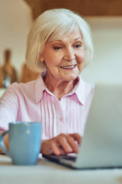 istock Happy senior lady working with gadget on the kitchen 1282480111