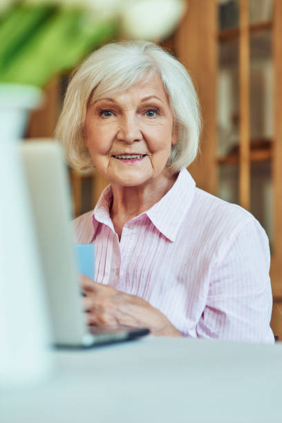 istock Positive gray haired lady working with computer in the room 1282480140