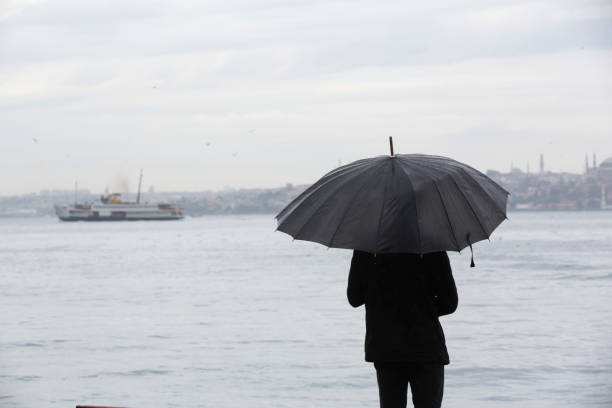 istock Man standing by the sea with black umbrella 1282481030