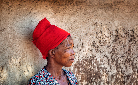 portrait of an old African woman next to the wall  in her village in Botswana