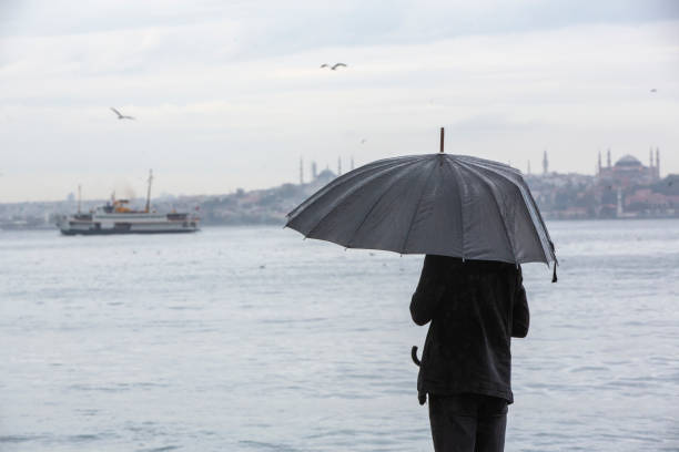 istock Man standing by the sea with black umbrella 1282482842