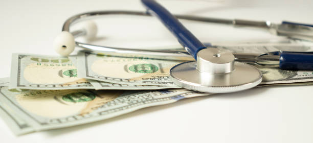 istock Envelope with money and a stethoscope on wooden background 1282487140