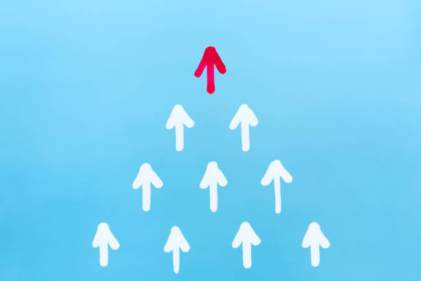 Leadership concept with red arrow leading among white arrows on blue background